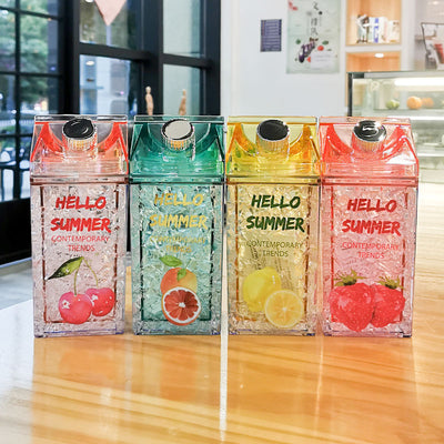 Colorful summer-themed vacuum cups with fruit designs and lids on a wooden table.